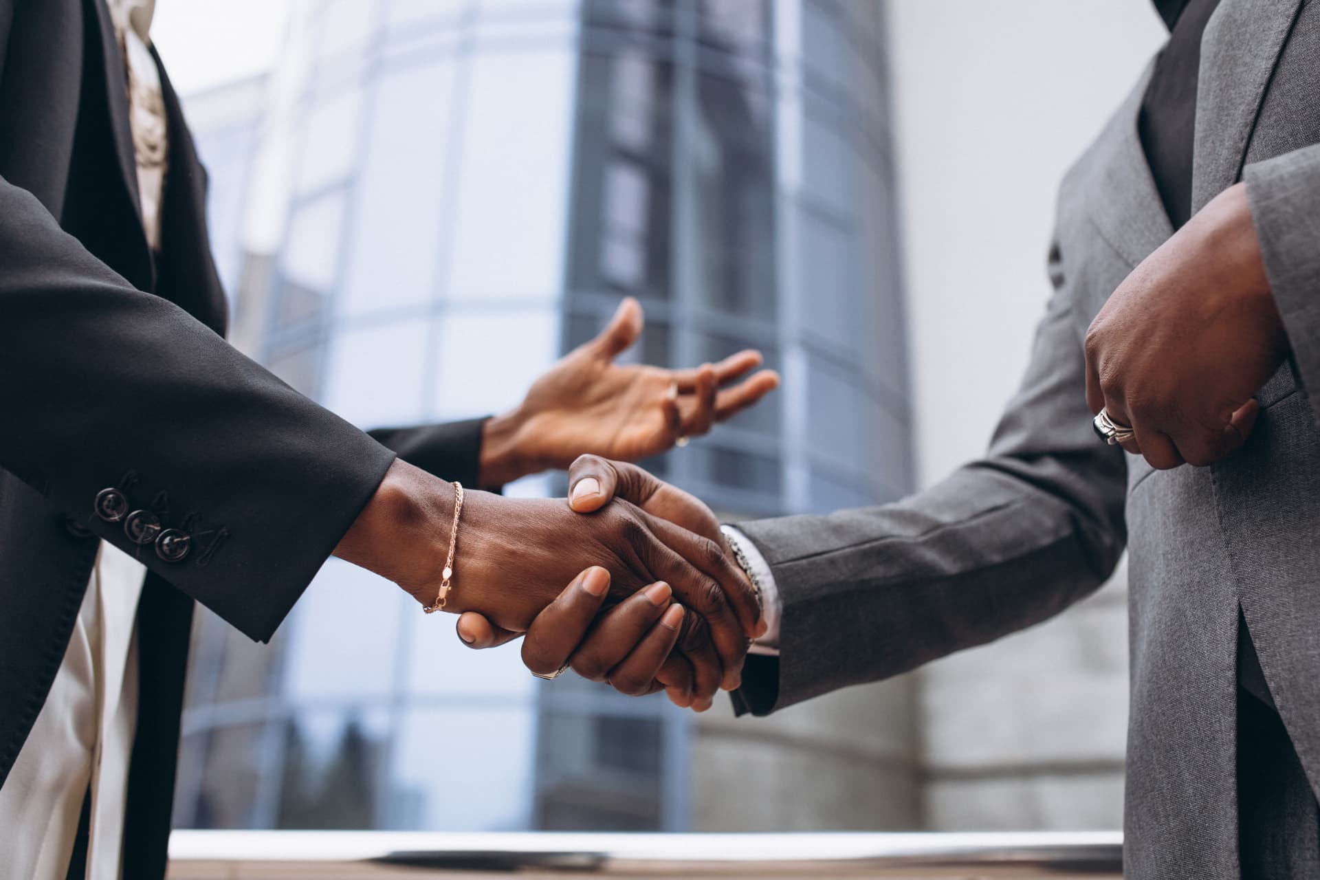Two business professionals shaking hands outside a modern office building